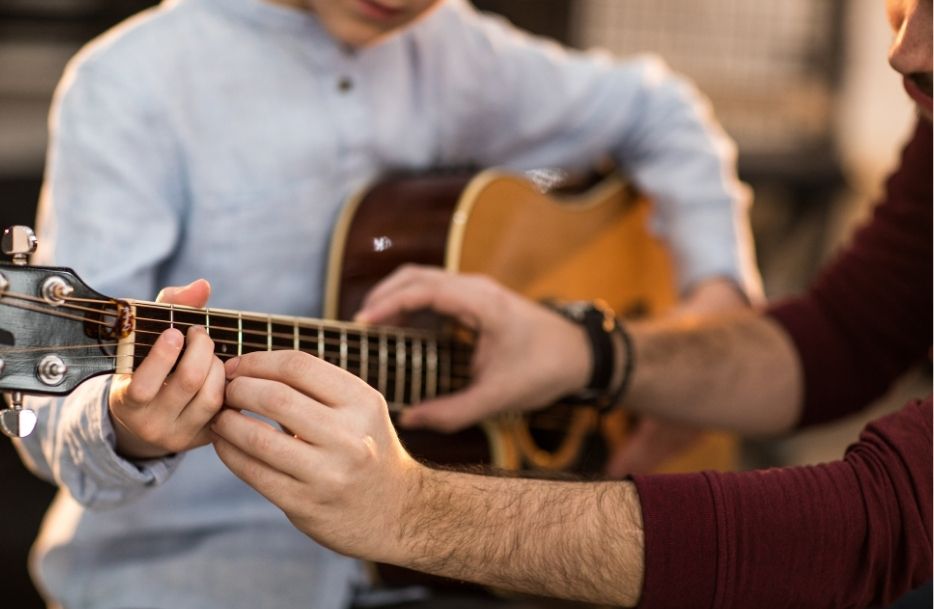 child learning playing guitar